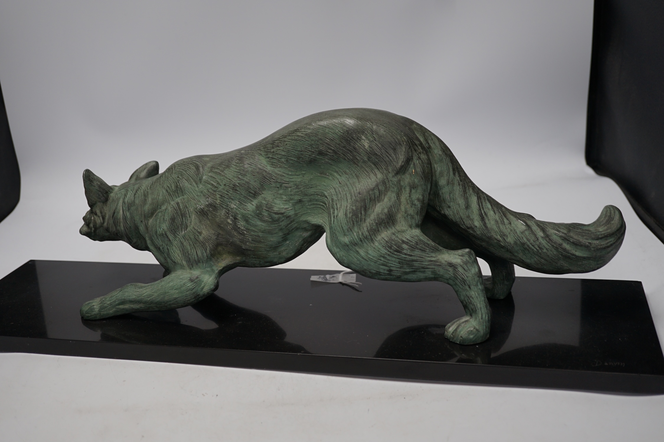 A bronzed metal model of a stalking fox, on black marble plinth, 62cm